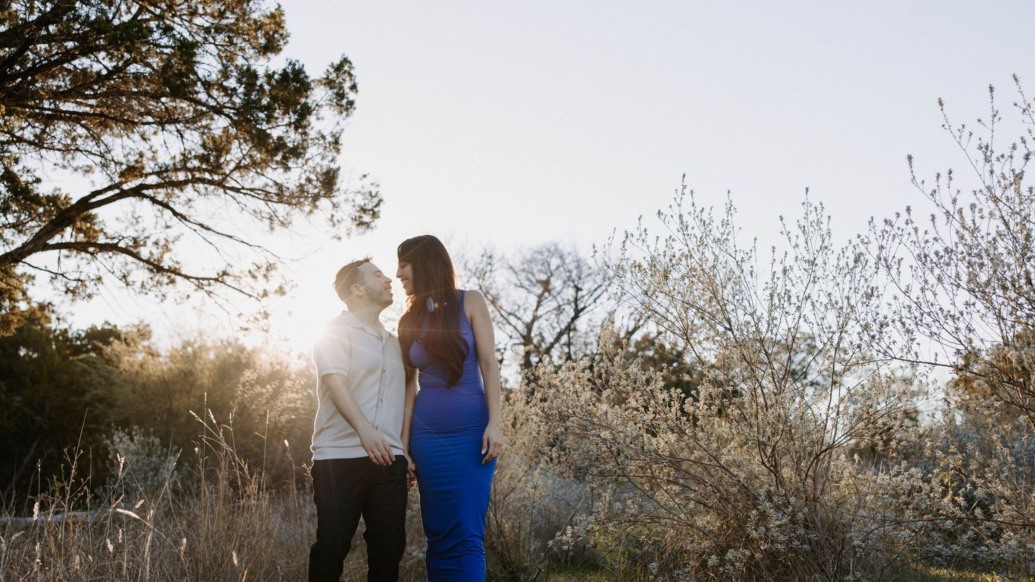 San Antonio Engagement Photography. A couple stands in silhouette against a bright sunset in a natural outdoor setting.