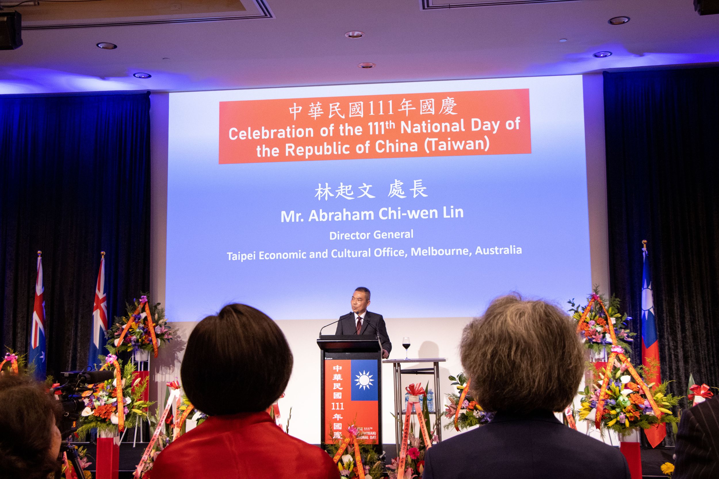 Speaker presents at Taiwan National Day celebration with flags and decorations.