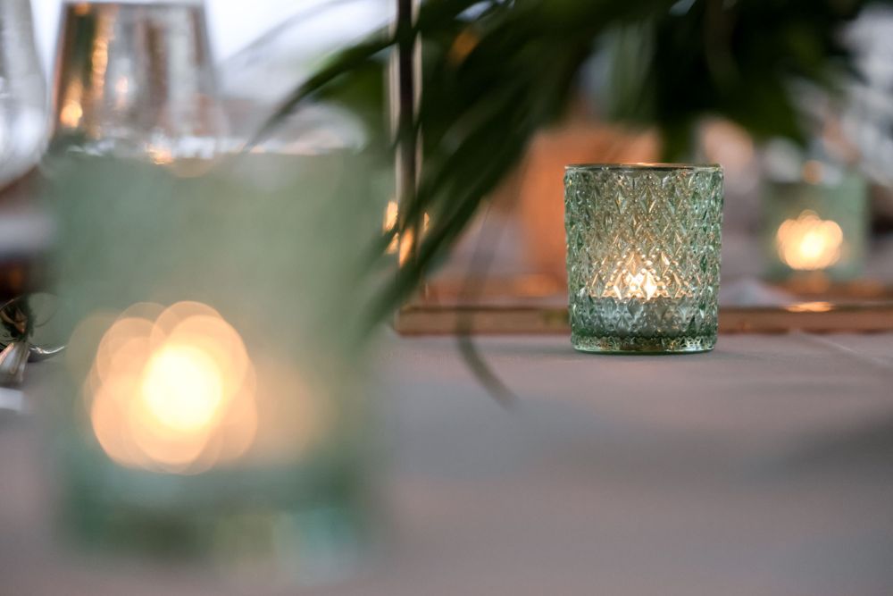 Glowing blue glass tea light holders create ambient lighting on an elegant table setting.