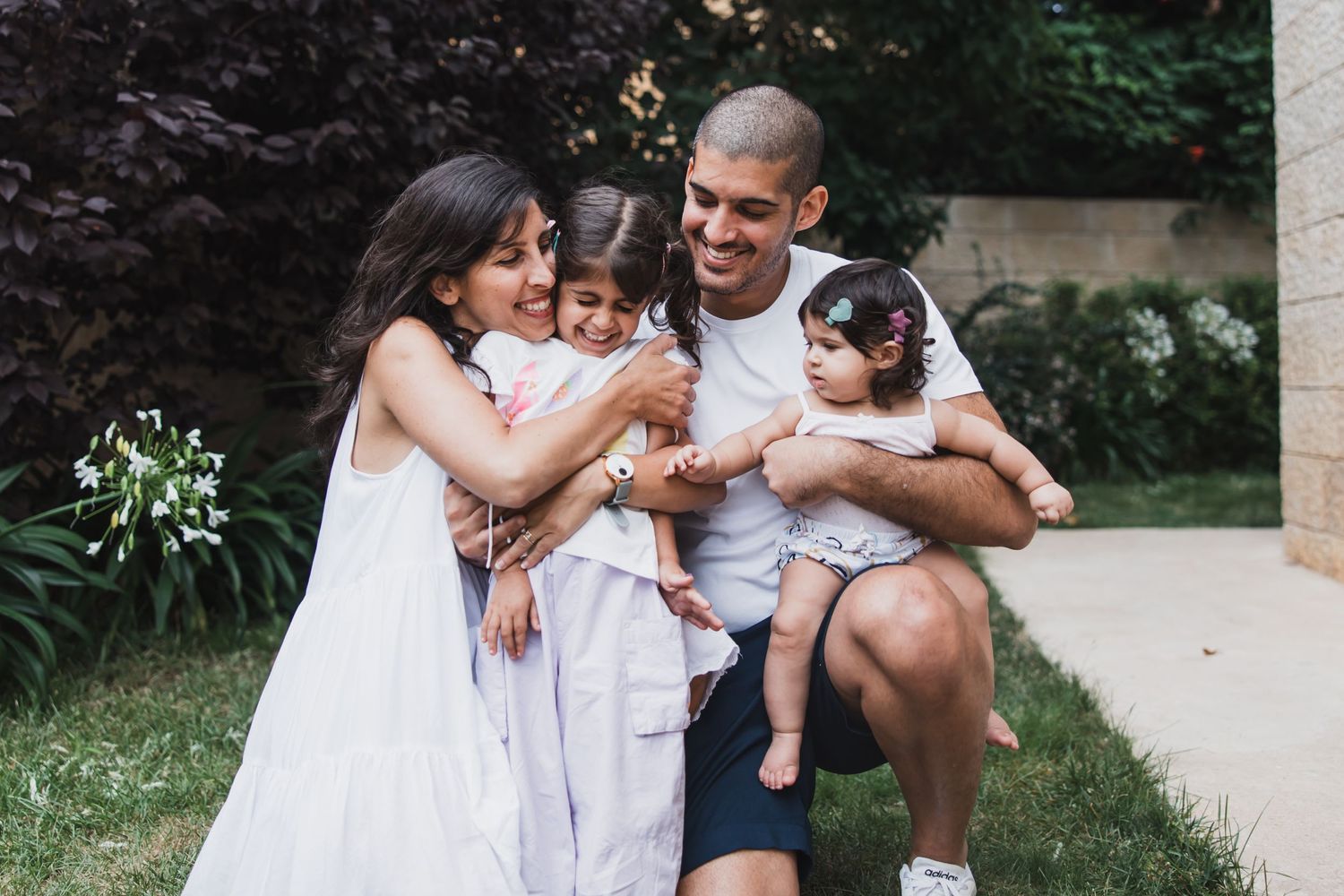 A tender family moment outdoors in summer garden setting.