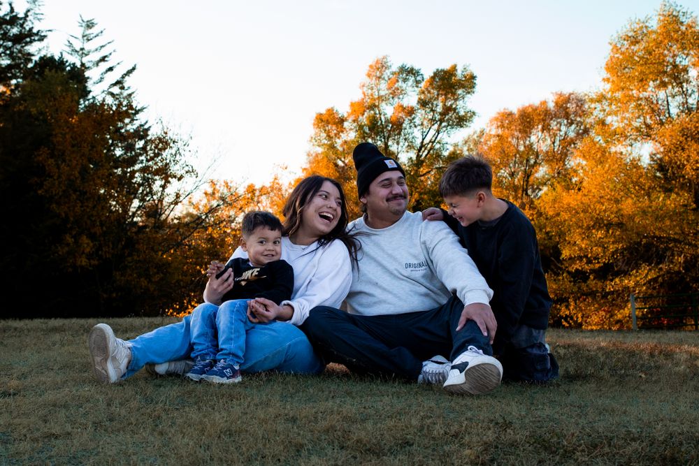 Young family of four laughs together at Cottonmill Park, Kearney, NE.