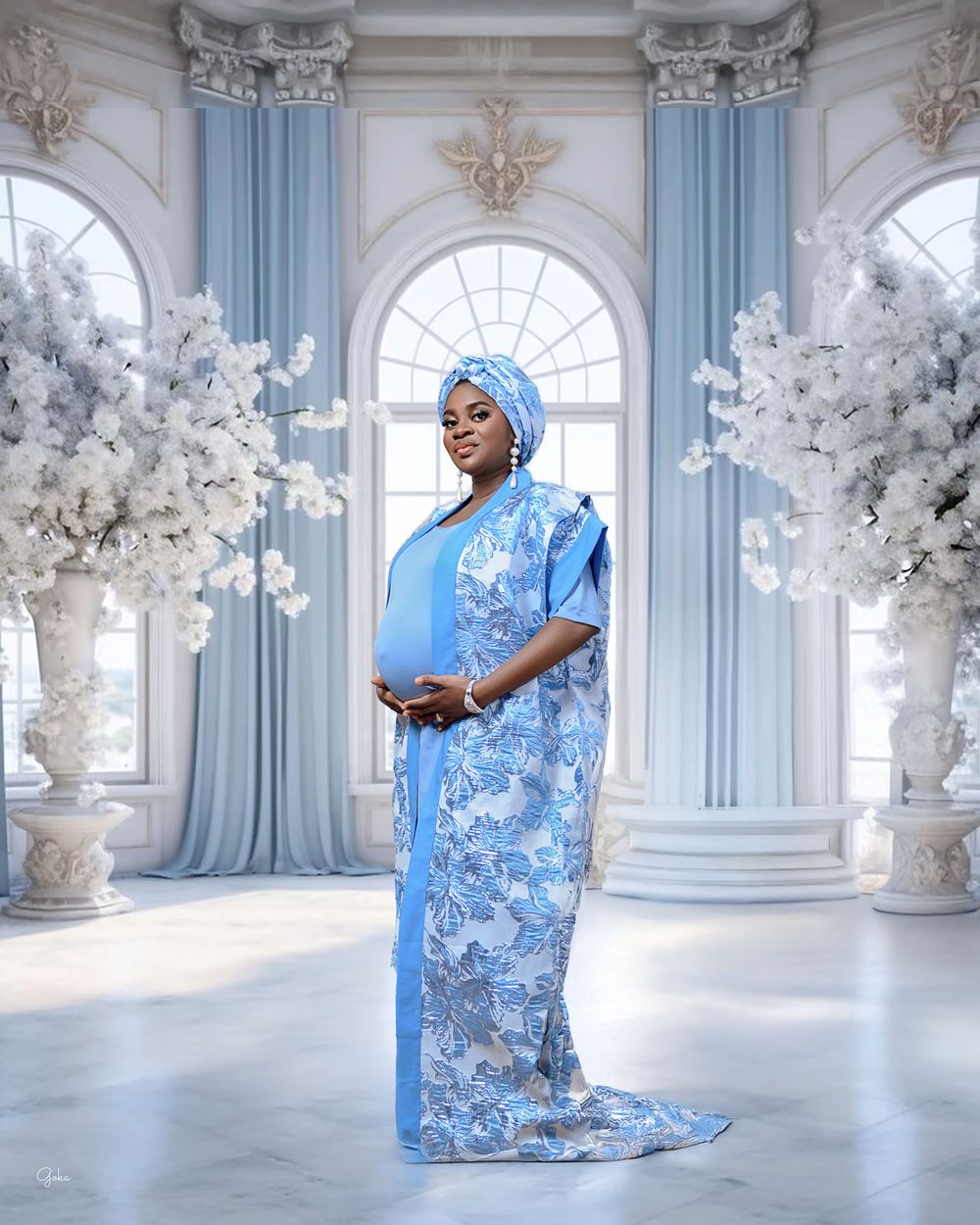 A regal figure in a flowing blue patterned dress and matching headwrap stands in an elegant white palace room with floral decor.