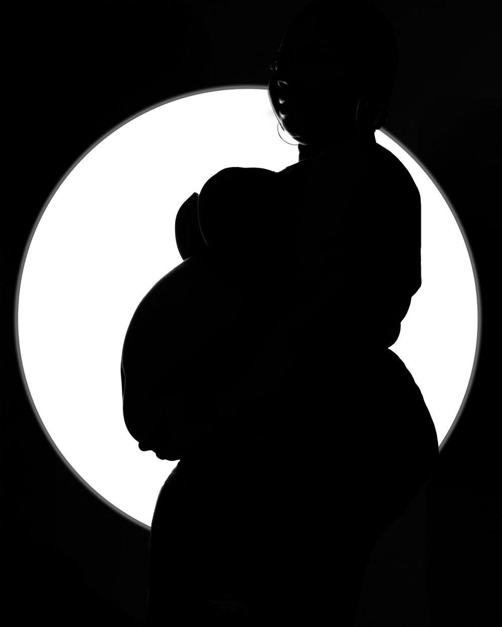 Dramatic silhouette of a figure against a bright circular light creating a stark black and white contrast.