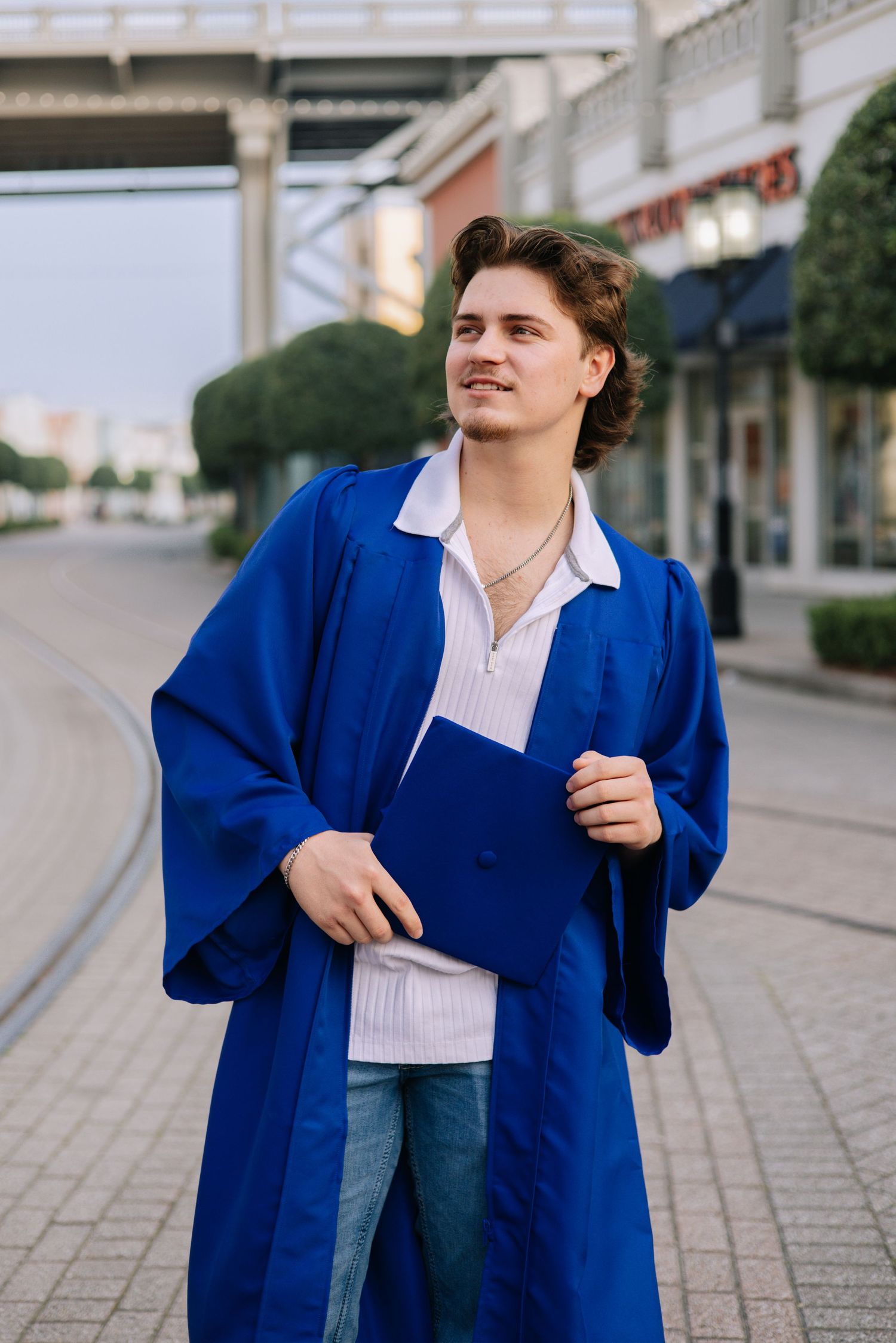 Person in bright blue coat and jeans poses confidently on urban street.
