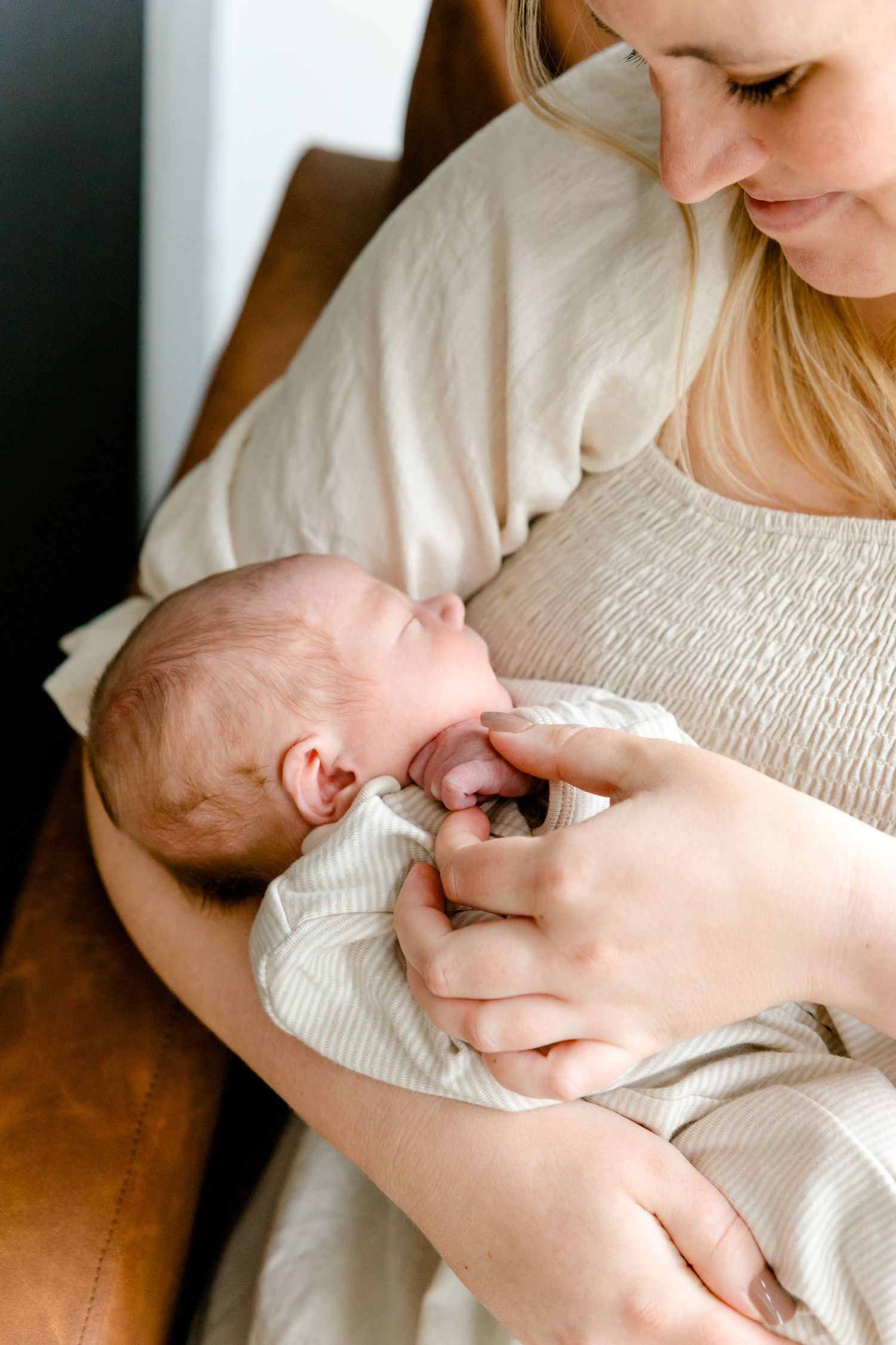 Close-up of mother in cream dress tenderly holding and gazing at her newborn baby.