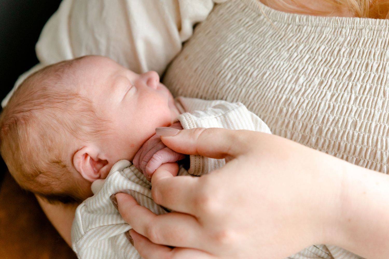 Close-up of newborn baby resting peacefully in mothers gentle arms.