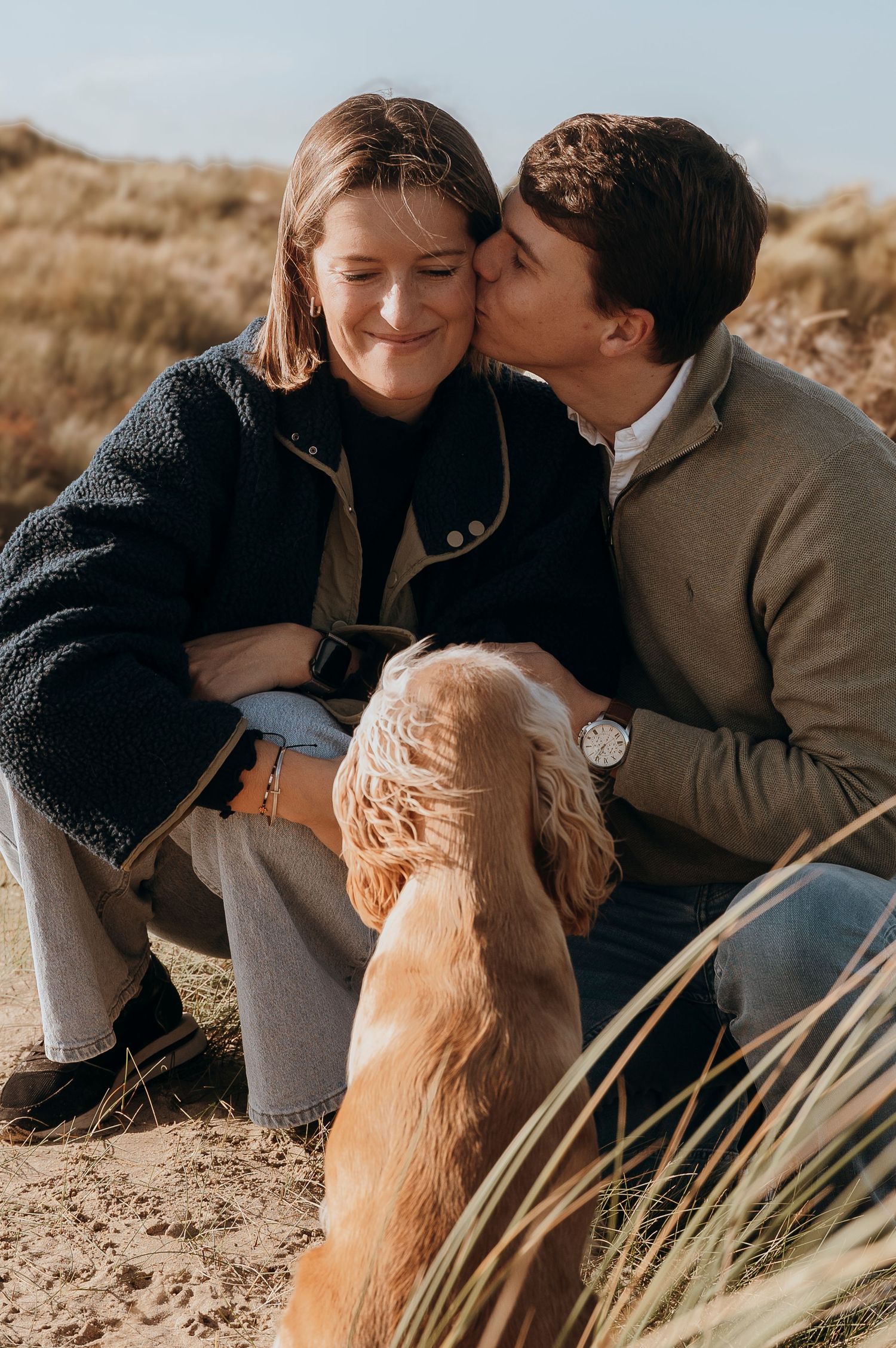 A heartwarming family moment in a sunlit meadow with tall golden grass swaying in the breeze.
