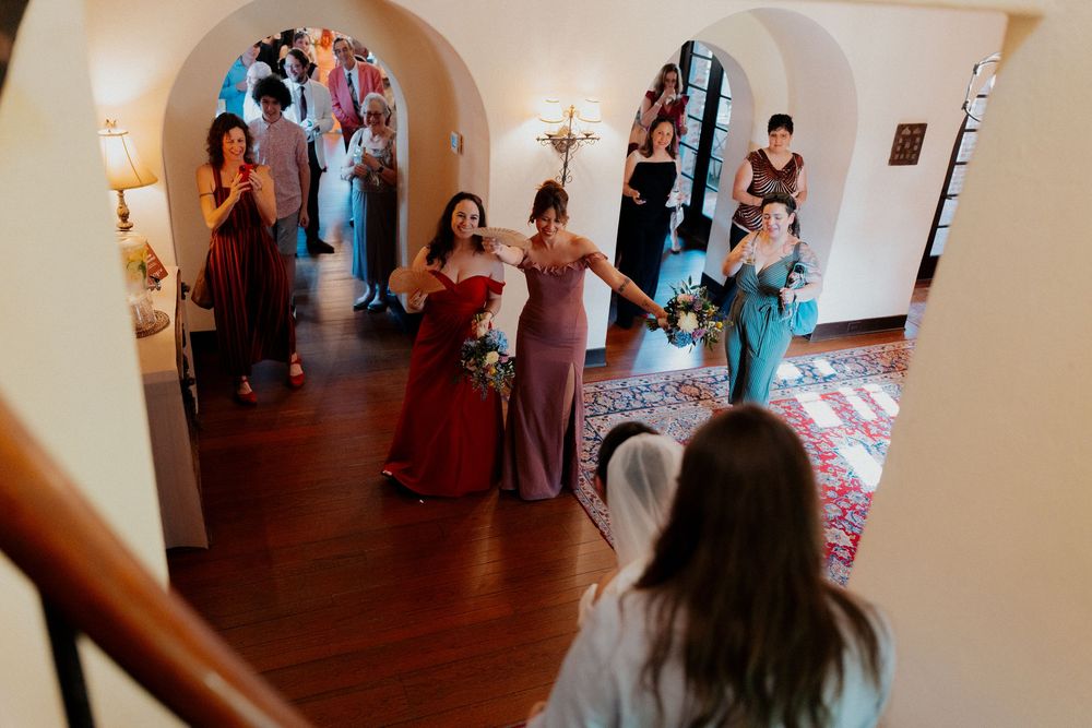 Wedding party gathering in an elegant hallway with arched doorways and warm lighting.