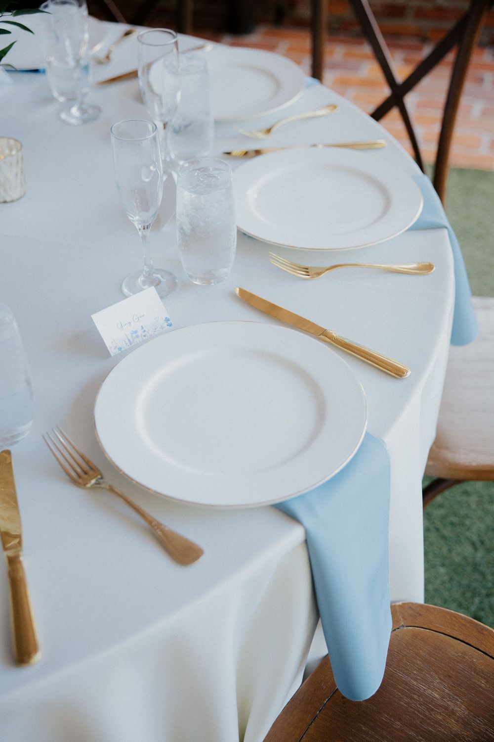 Elegant table settings with white linens, gold flatware, and light blue accents.