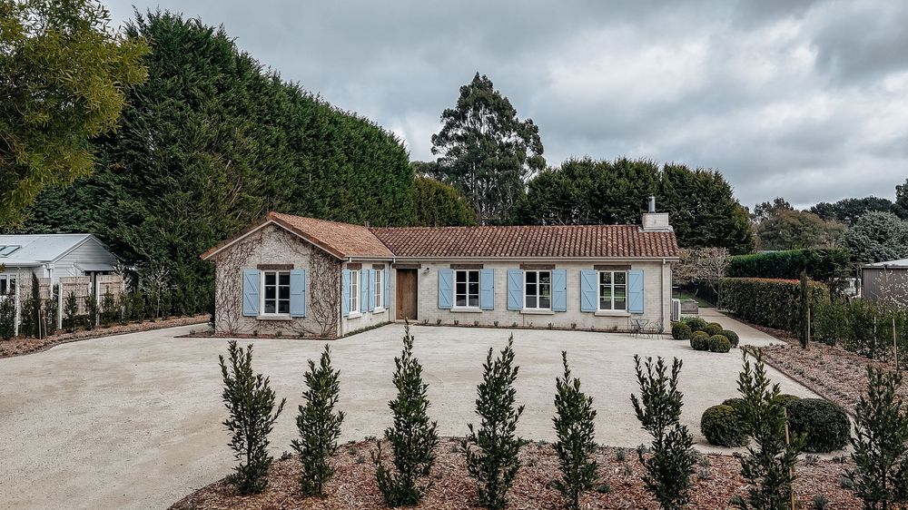 A panoramic view of a stone building complex with tiled roofs and windows under cloudy skies.