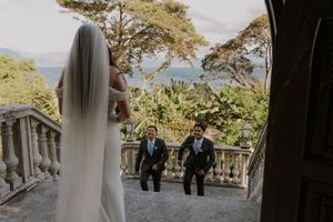 Wedding party gathered on a scenic outdoor terrace overlooking mountains and tropical landscape.