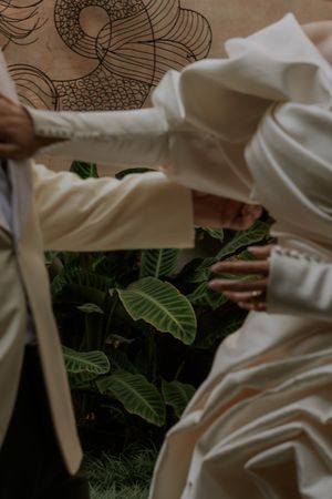 Flowing white fabric with tropical green leaves creating an elegant wedding detail.