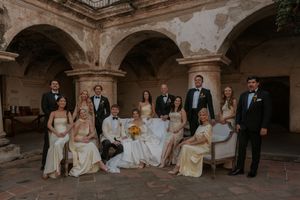 Wedding party poses together in a series of elegant photos under arched stone architecture.