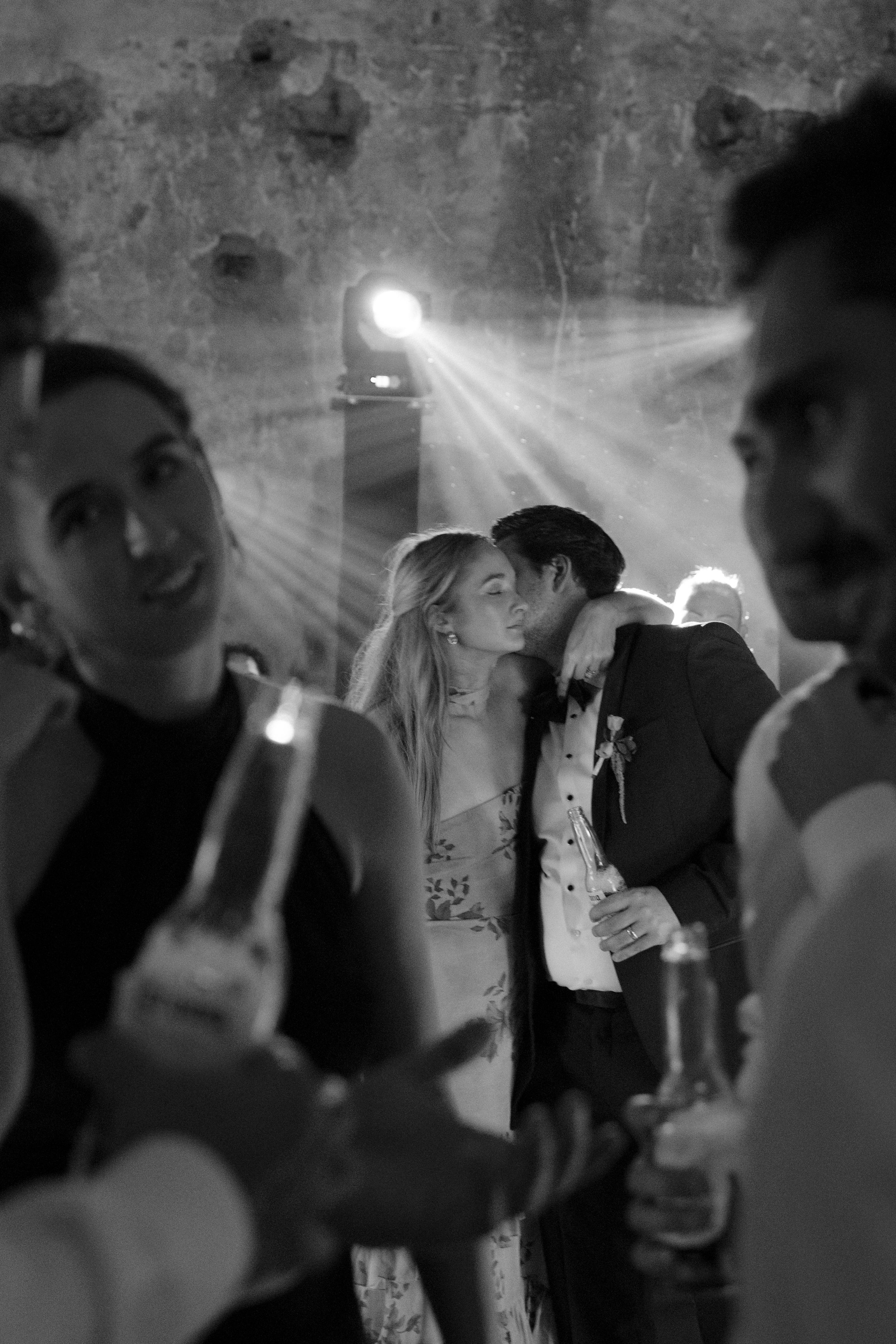 Wedding reception dance floor scene with silhouettes of guests and dramatic lighting effects.