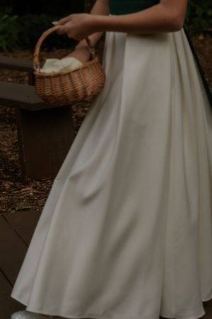 Close-up details of a flowing white wedding dress with delicate fabric movement and natural outdoor lighting.