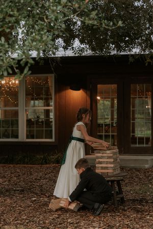 A romantic couple sits together on a bench surrounded by fallen leaves and twinkling lights in a cozy outdoor setting.
