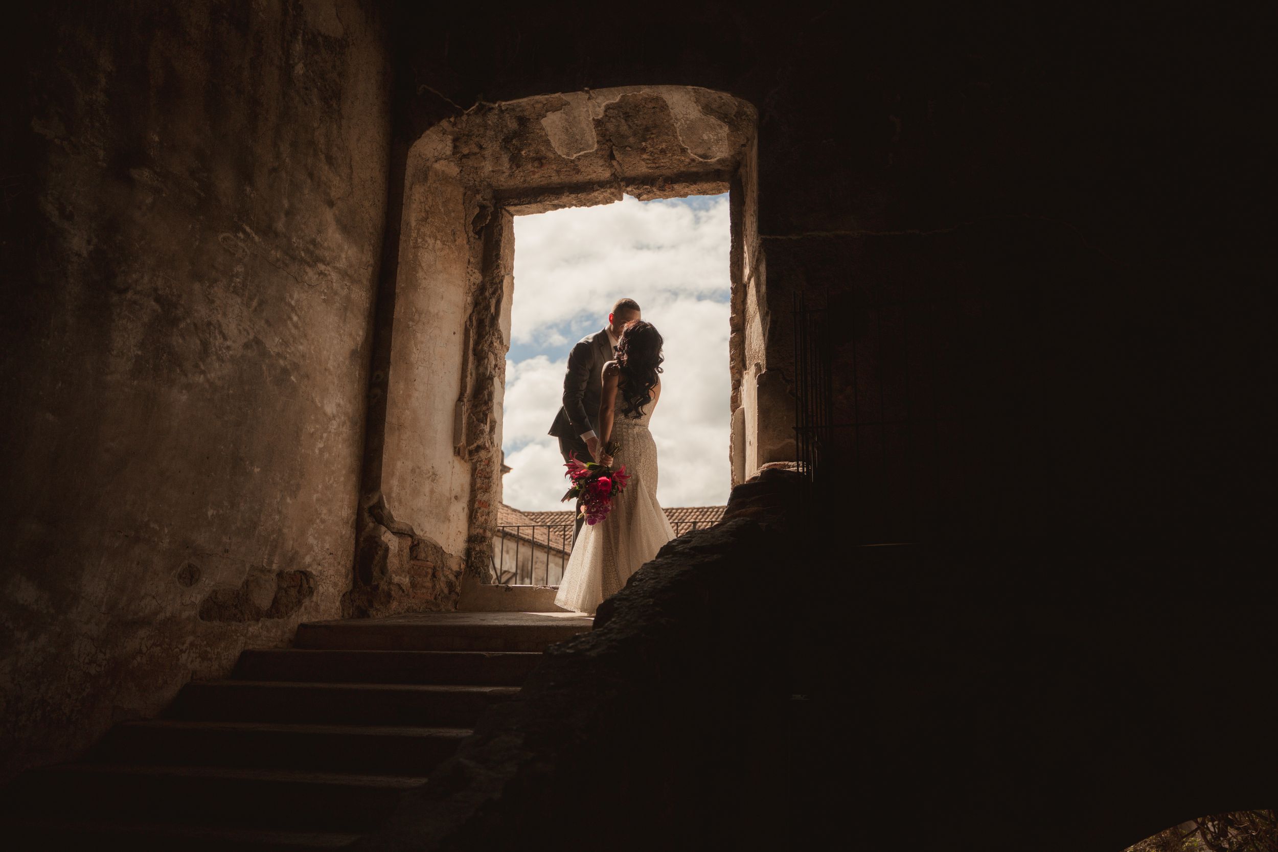 A series of dark stone archways and windows in an ancient castle corridor creates a dramatic shadowy atmosphere.