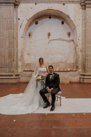 A series of wedding photos showing a couple in formal attire sitting in a rustic stone archway venue.