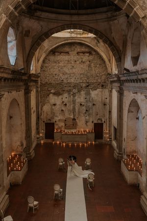 A rustic stone chapel interior with vaulted ceilings and glowing candles creating a romantic atmosphere.