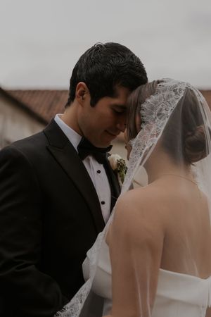 Elegant wedding couple in formal attire sharing a tender moment outdoors.