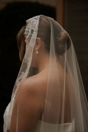 Close-up view of a delicate lace-trimmed bridal veil against a dark background.