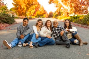 Friends sitting together on a road with golden autumn trees in the background.