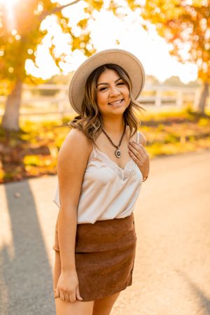 Fashion portrait in warm autumn lighting showcasing a casual chic outfit with beige hat and brown miniskirt.