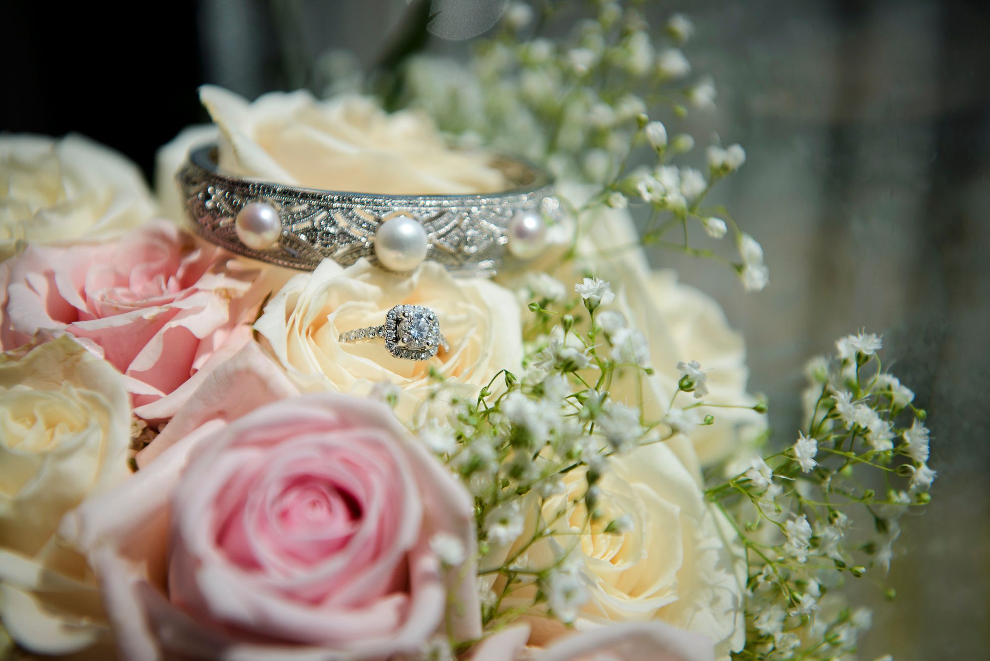 A delicate bouquet of pink and cream roses with baby's breath flowers arranged in a decorative vase.