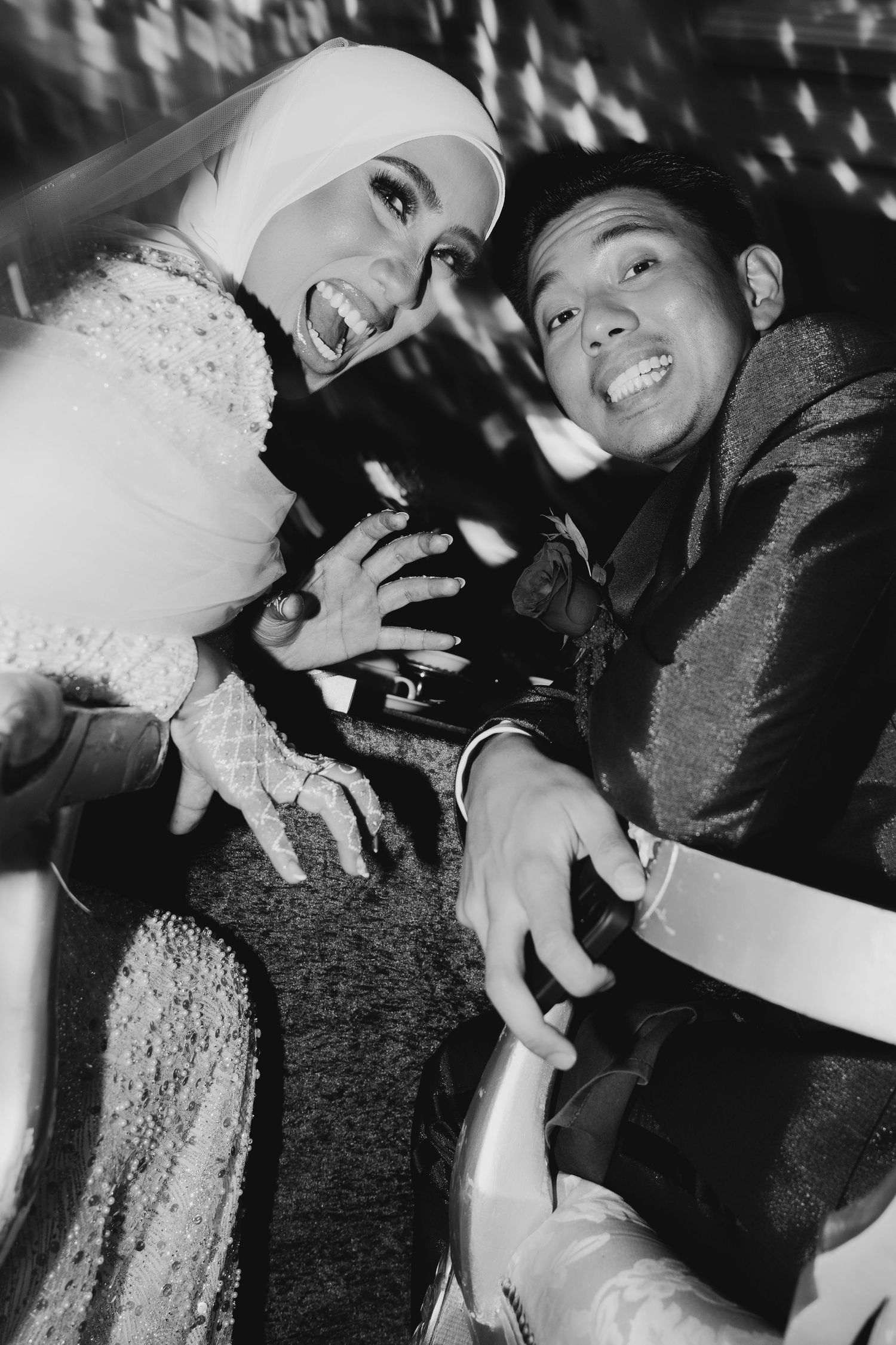 Joyful newlywed couple laughing together in black and white wedding reception photo.