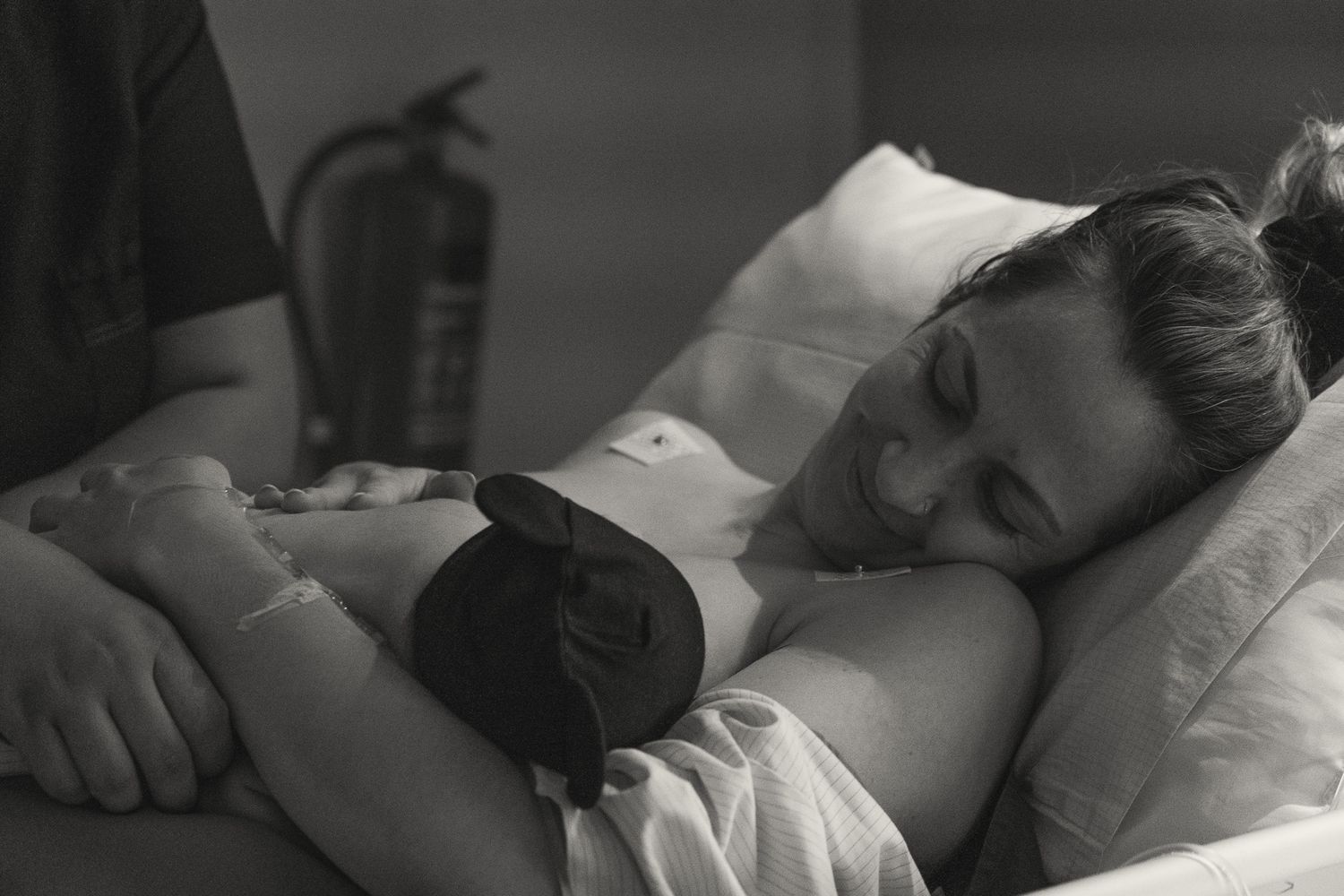 Black and white birth photography showing intimate skin-to-skin contact with newborn.