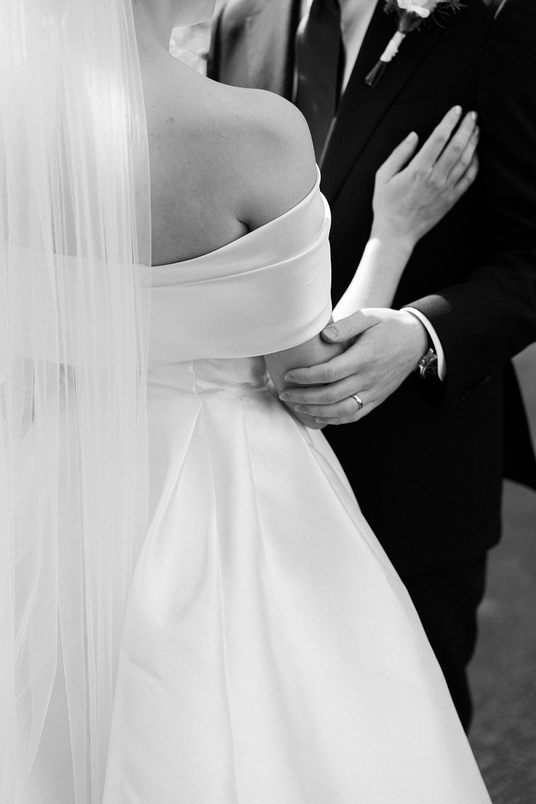 Black and white wedding photo series showing close-up details of a bride's white dress and veil.