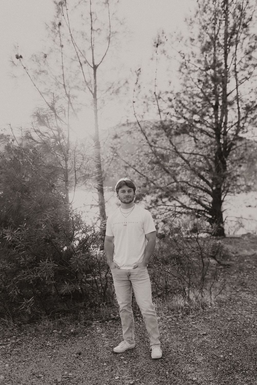 Black and white photo showing someone walking through a wooded area wearing white clothing.