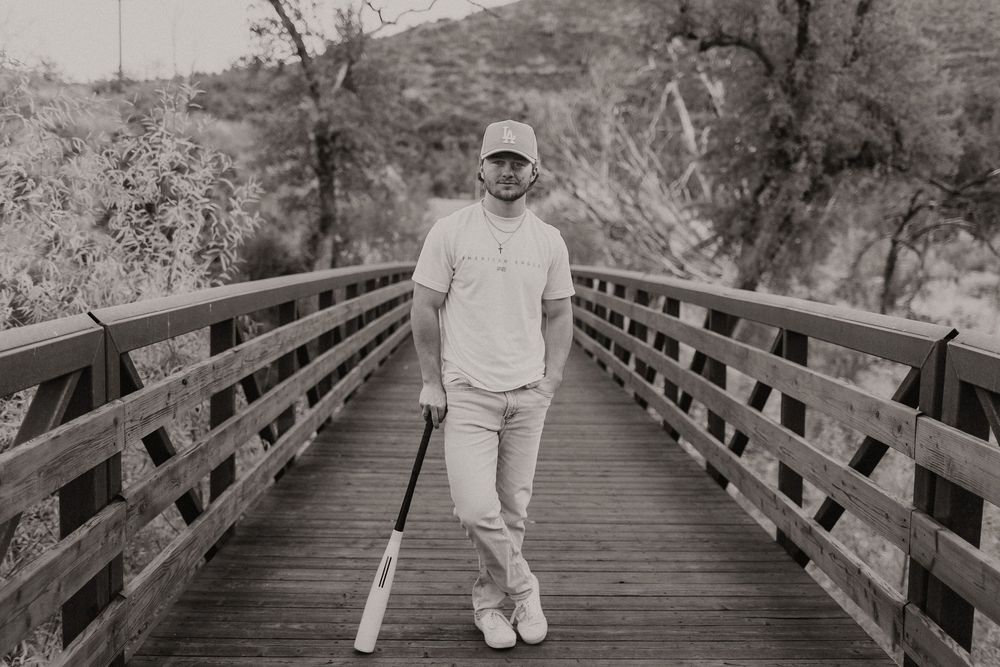 Person in white clothing walks along a wooden bridge pathway through scenic natural surroundings.