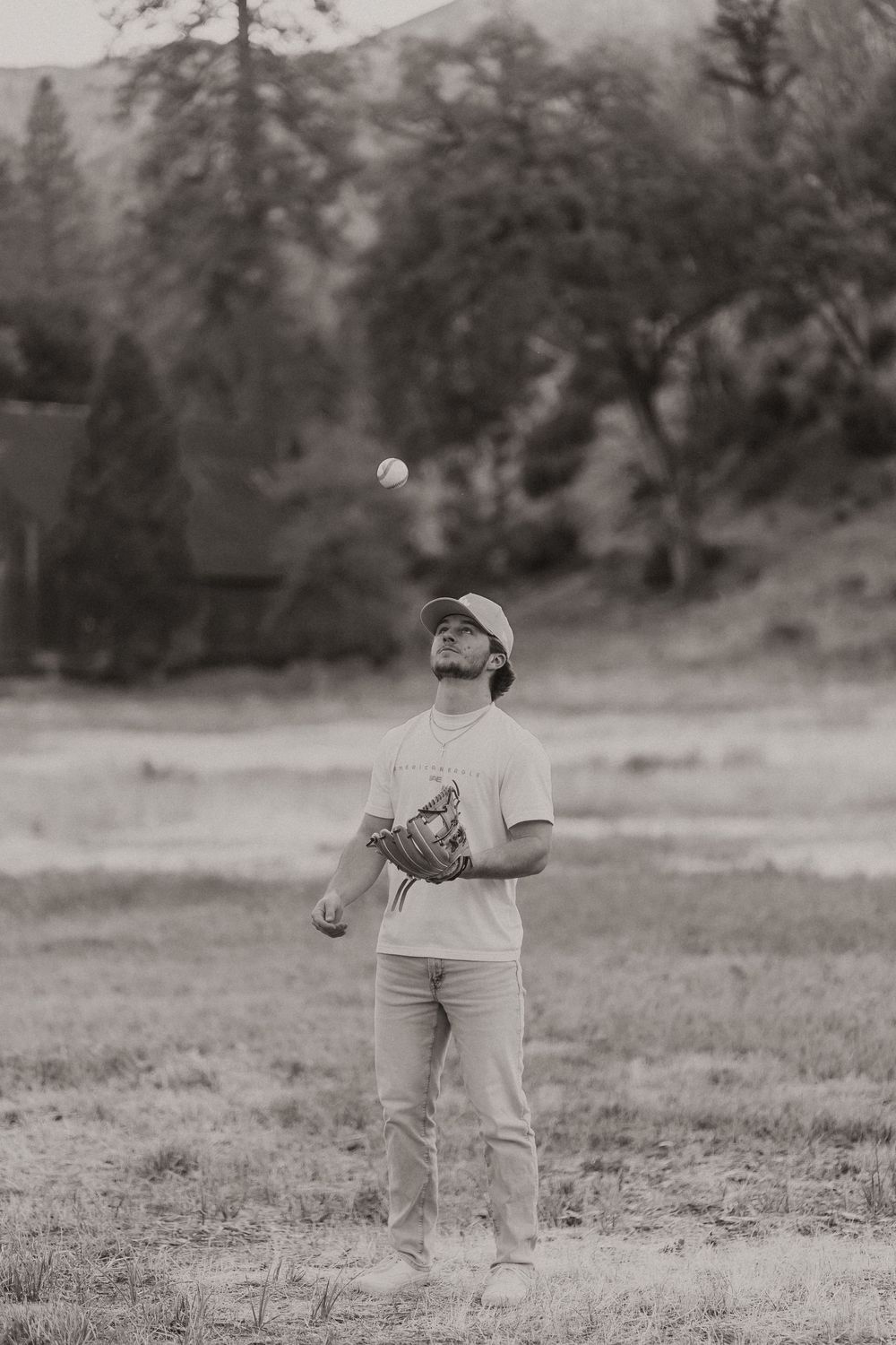 Black and white image of someone playing catch with a baseball in an open field.