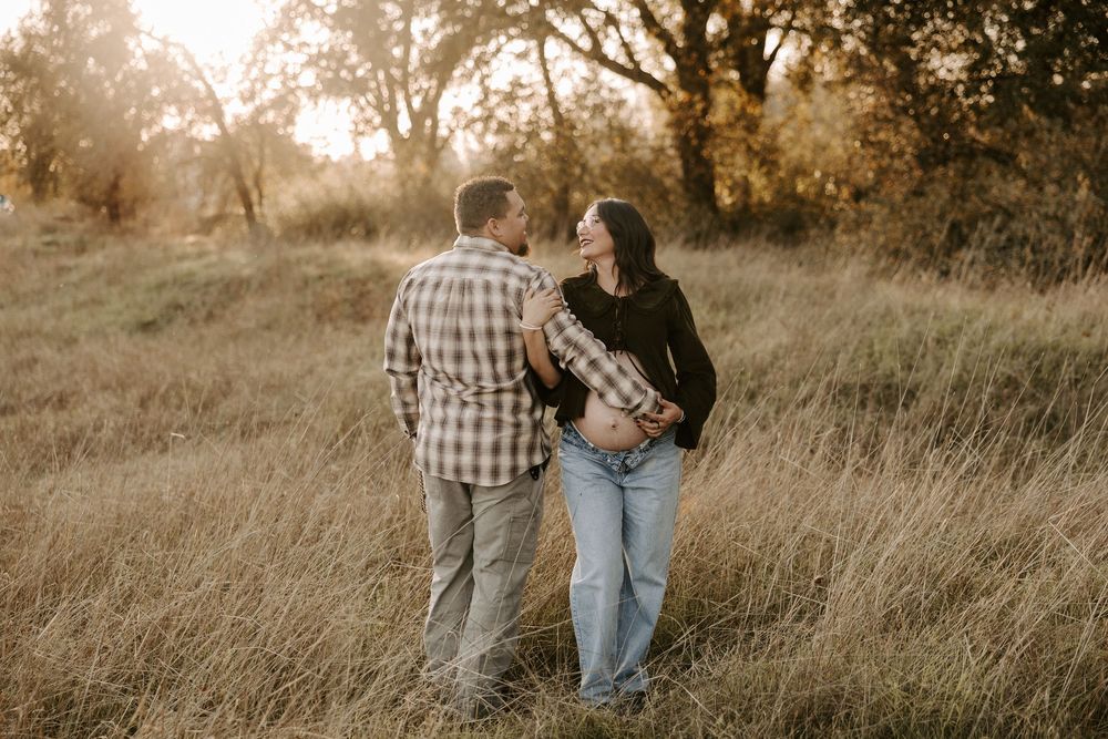 A couple walks hand in hand through a golden field at sunset creating a romantic silhouette.