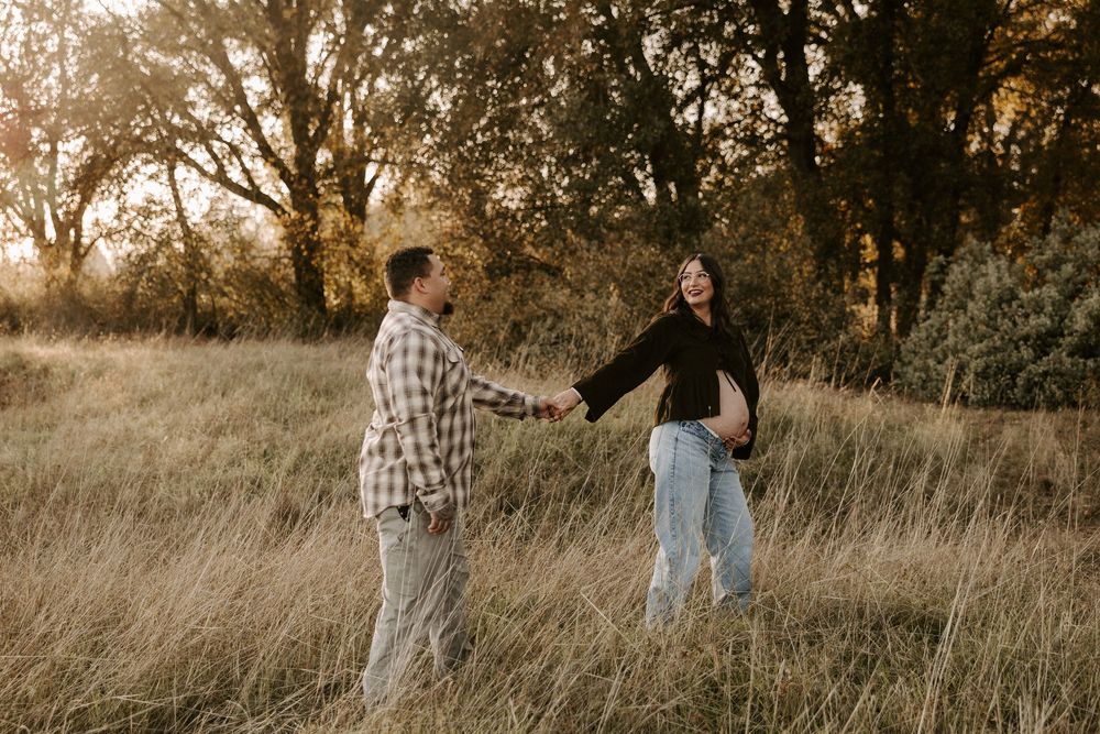 Couple walking together through a golden autumn field at sunset during a romantic photoshoot session.