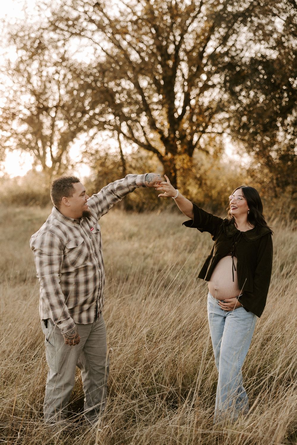 A couple shares romantic moments together in a golden field of tall grass during sunset.