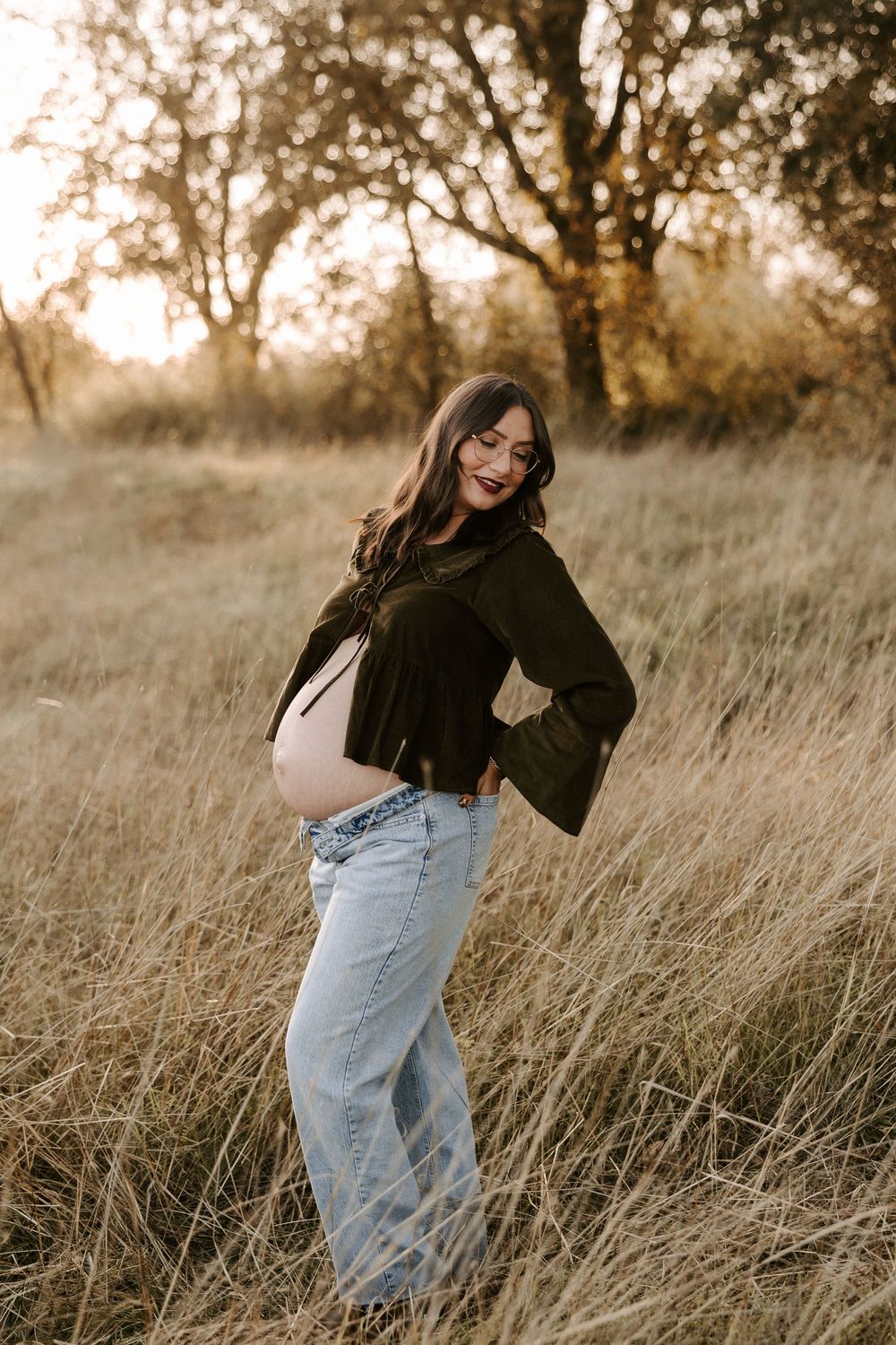 A series of artistic portraits showing movement in tall autumn grass wearing jeans and a black top.