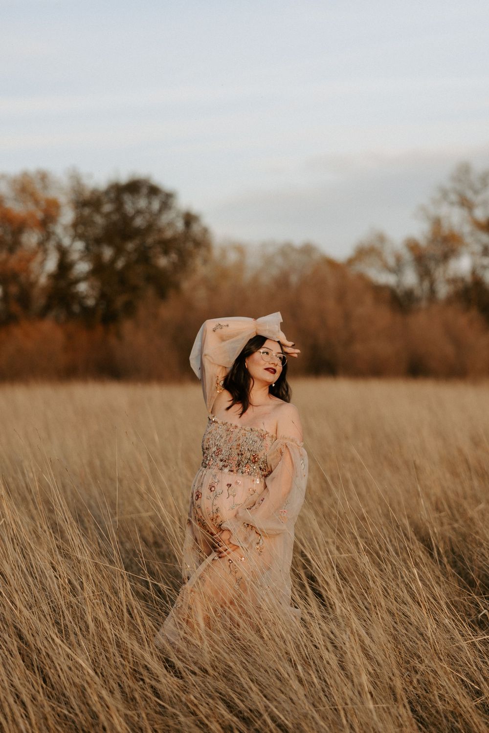 Ethereal portraits in a golden field showing graceful movement in a floral dress at sunset.