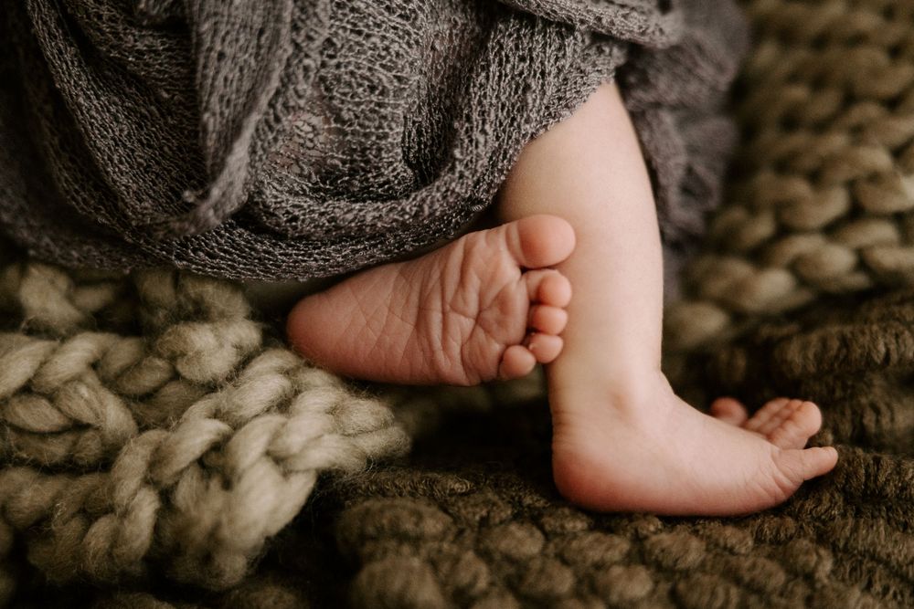Close-up view of tiny newborn baby feet in a soft knit blanket.