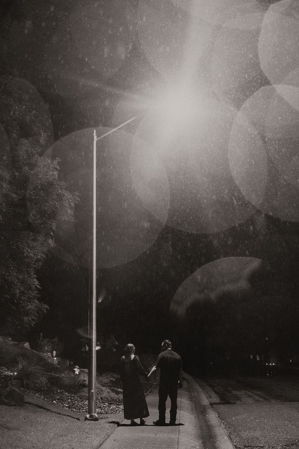 A sequence of dark atmospheric photos shows people gathering near a tall light pole at night creating an eerie mood.