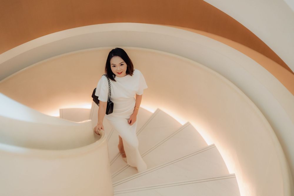 Person in white dress lies gracefully on curved architectural surface with dramatic lighting and shadows.