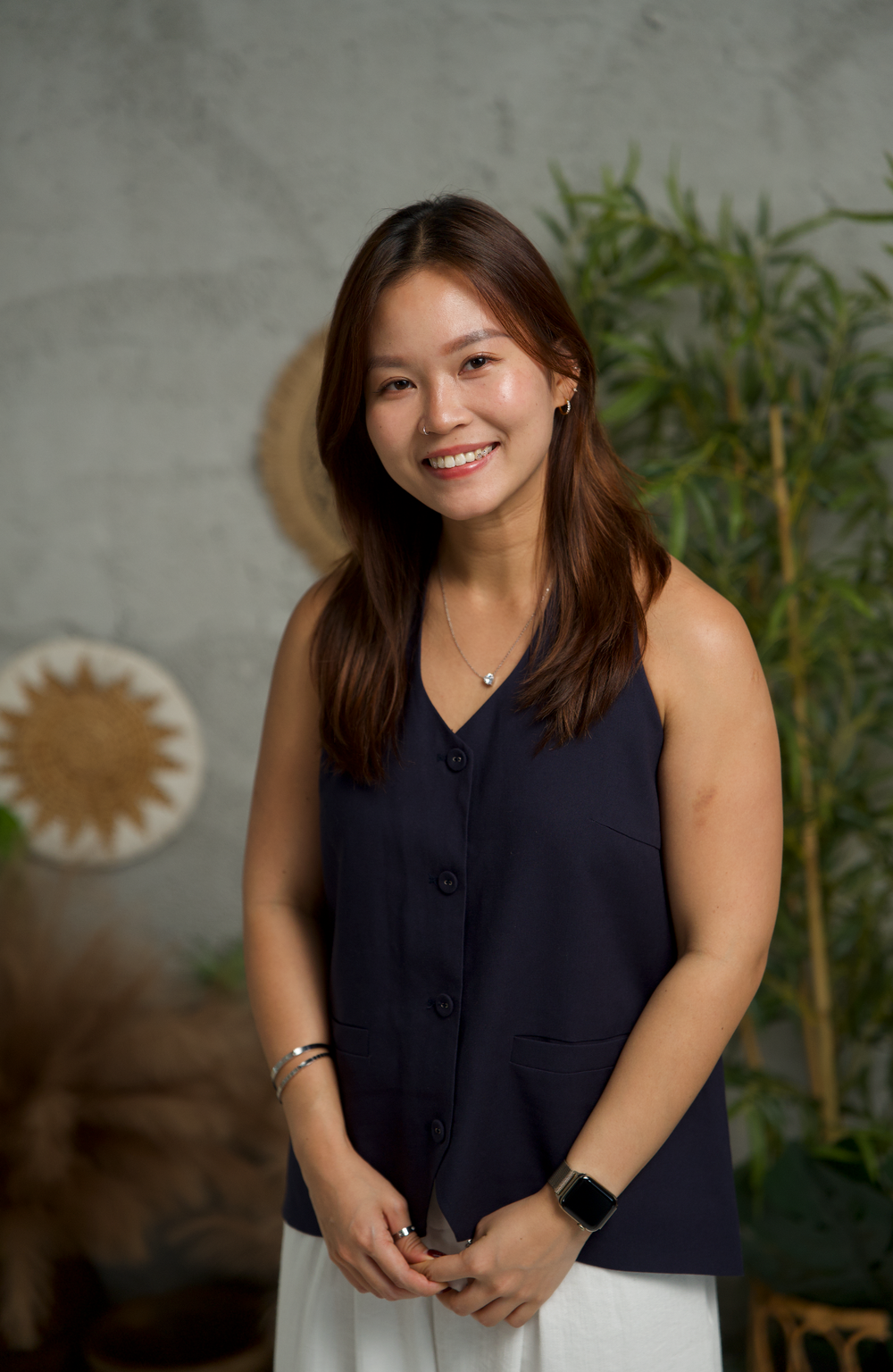 Lifestyle portraits with greenery backdrop featuring someone in a sleeveless navy top.