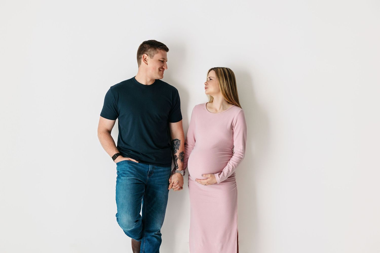 Family maternity portrait taken in Middle Tennessee studio with mom and dad on minimalist white studio wall