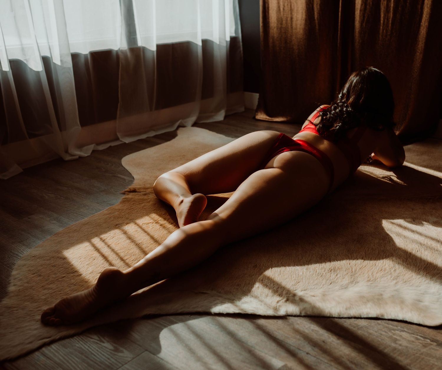 Sunlight streaming through window creates dramatic shadows on wooden floor with Wisconsin boudoir photographer.