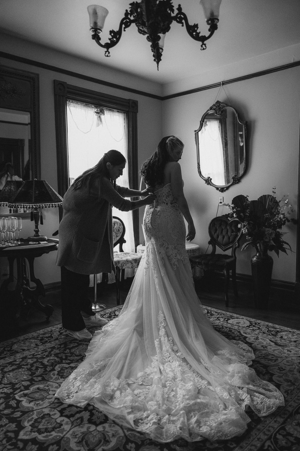 A series of black and white photos showing a wedding dress with intricate lace details and flowing train.