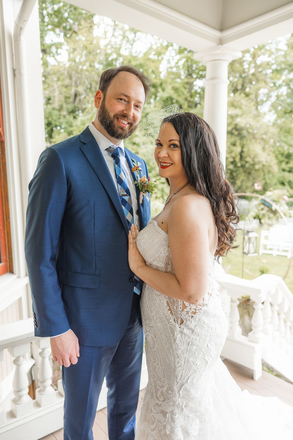 A couple shares intimate moments on an elegant white porch during their wedding day.