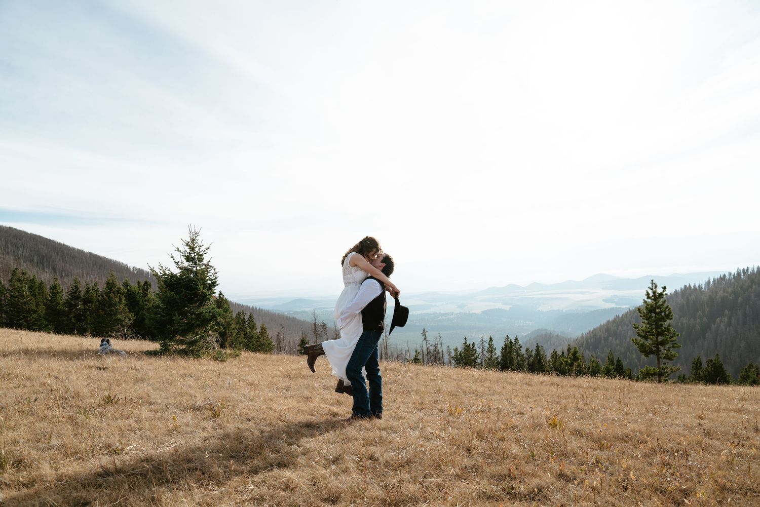 Groom picks up bride and kisses her on top of a mountain. Montana elopement photographer.