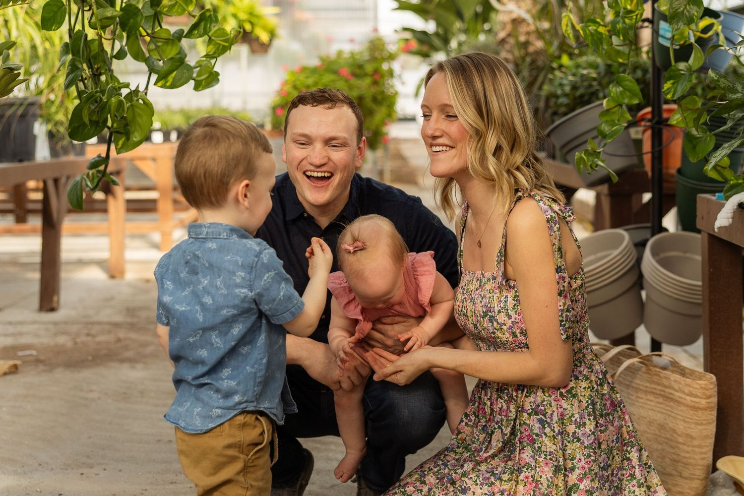 Family laughing together while spending time in plant-filled greenhouse.
