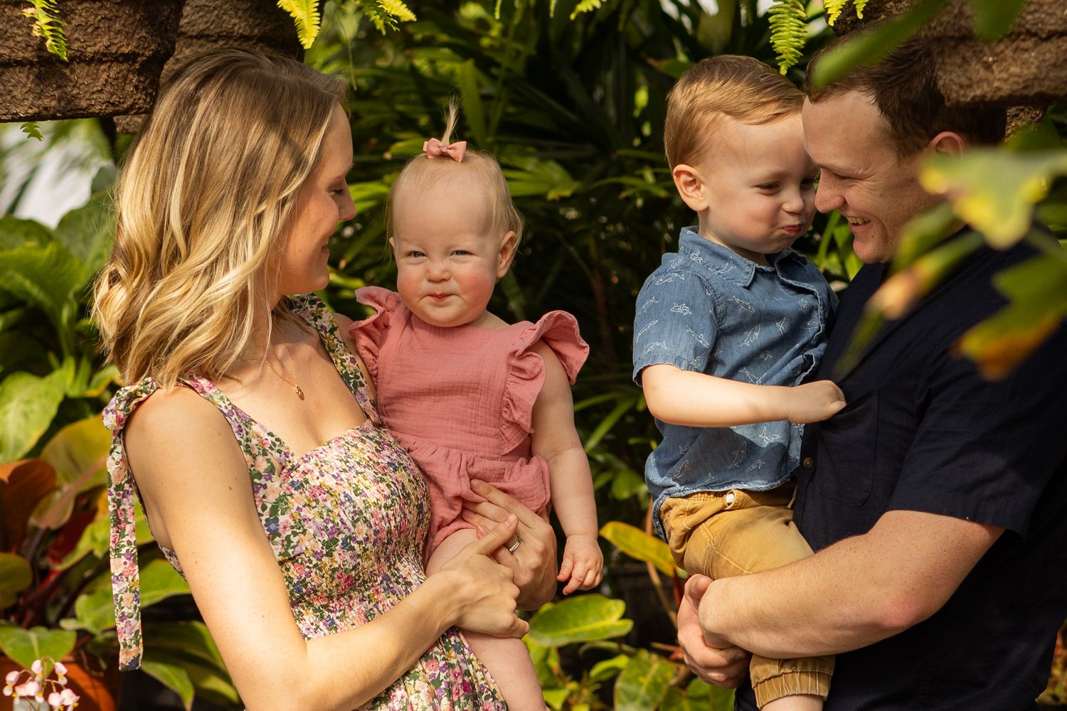 A family moment captured in a lush garden setting with hanging plants.